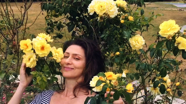 Maria Fernanda Cândido ao redor de flores amarelas