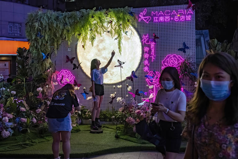 Amigas tiram fotos em painel no bairro de Jiangnanxi