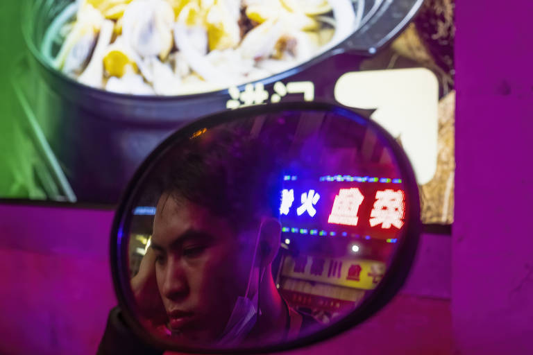 Entregador aguarda serviço em Taojin, na periferia de Cantã