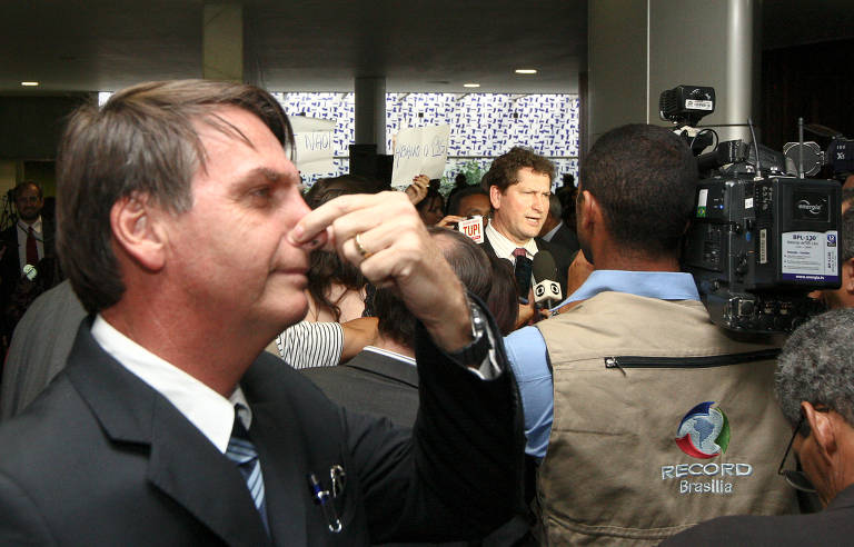 O então deputado Jair Bolsonaro tampa o nariz durante a entrevista do então deputado Jilmar Tatto