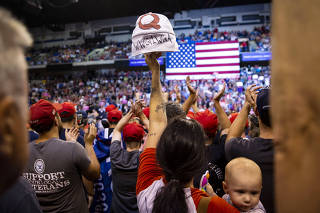 A woman holds up a hat with a Q on it, denoting QAnon, during a rally with President Donald Trump in Avoca, Penn., Aug. 2, 2018. (Al Drago/The New York Times)