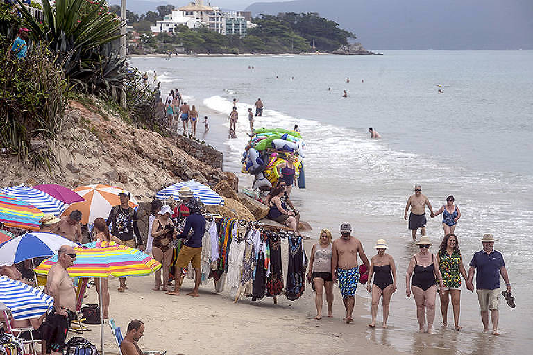 Turistas e ambulantes dividem o pequeno espaço de areia em Canasvieiras