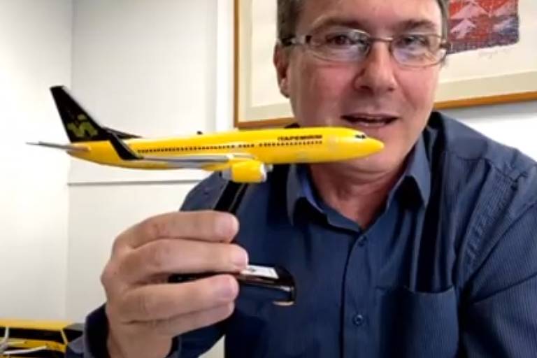 Presidente da Ita Transporte Aéreo em camisa azul-escuro segura miniatura de avião pintado de amarelo