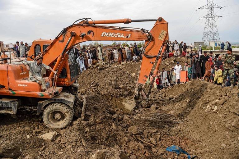 Escavadeira auxilia buscas por sobreviventes nas ruínas de uma casa destruída pela enchente em Chanrikar, no Afeganistão
