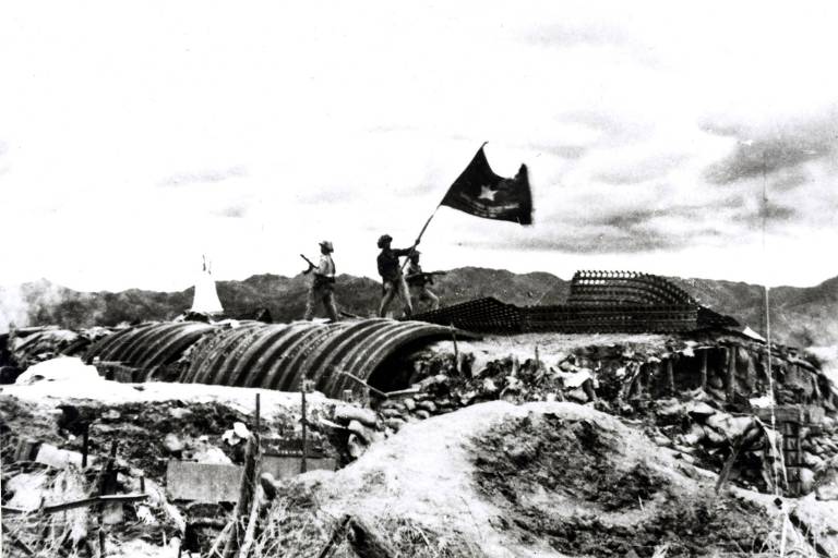 Soldados vietnamitas erguem bandeira do país em meio a escombros 