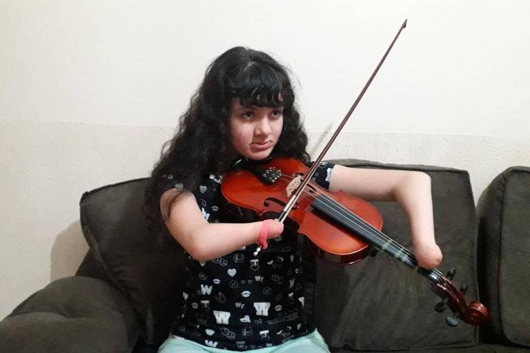 Adolescente apaixonada por violino usa adaptações para driblar deficiência e tocar instrumento