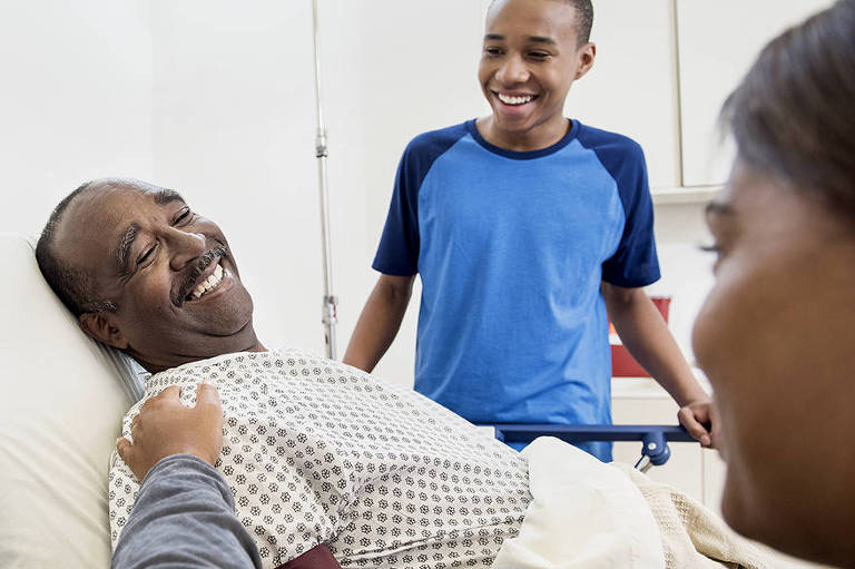 Paciente sorrindo entre familiares em ambiente hospitalar