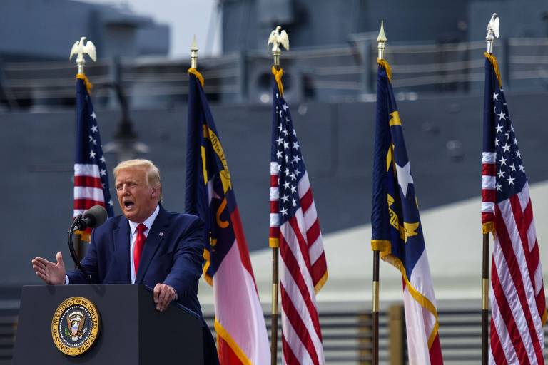 Trump fala com navio de guerra ao fundo