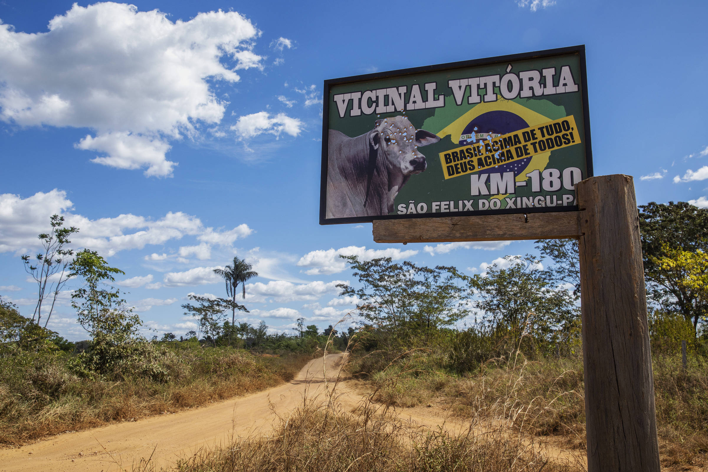 Placa indicando uma estrada vicinal dentro da Terra Indígena Apyterewa, no Pará, com marcas de tiro e um adesivo de apoio ao presidente Jair Bolsonaro