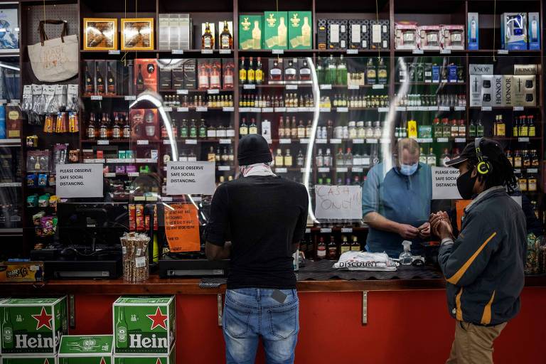 Cliente compra álcool em loja de bebidas de Joanesburgo, após governo sul-africano permitir venda de bebidas alcóolicas, que ficou proibida devido à pandemia de coronavírus