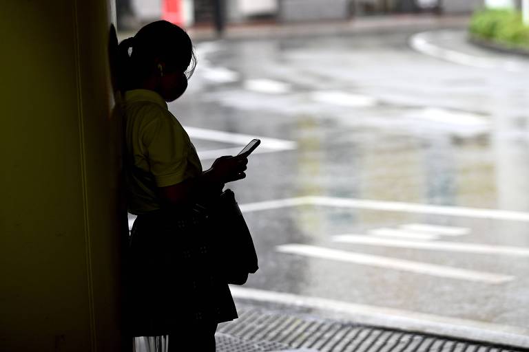 Silhueta de garota que mexe em celular no Japão