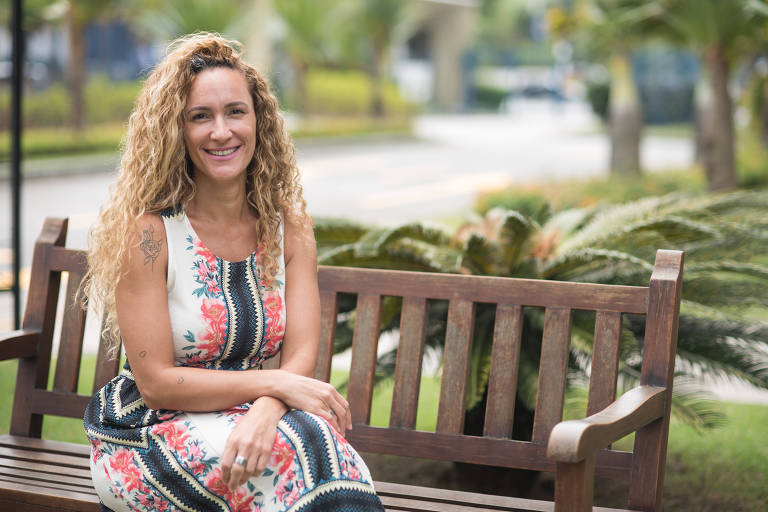 Glenda Moreira, head de diversidade Latam da Novartis, sentada em um banco, sorrindo