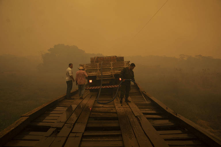 Voluntários monitoram ponte de madeira contra incêndio florestal na rodovia Transpantaneira, no Pantanal Mato-Grossense; mais de 15% da área do Pantanal foi destruída pelo fogo