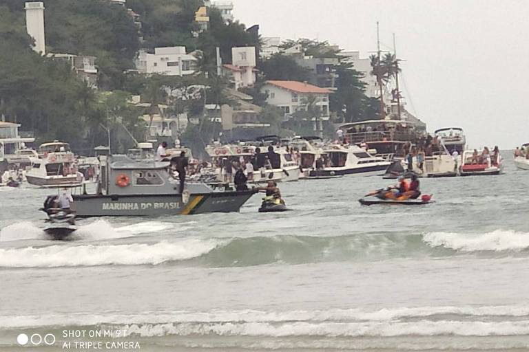 Prefeitura acionou a PM e a Capitania dos Portos para encerrar festa clandestina em Guarujá; veem-se barcos policiais e outros, tipo lanchas e pequenos iates, no mar, num canto de praia