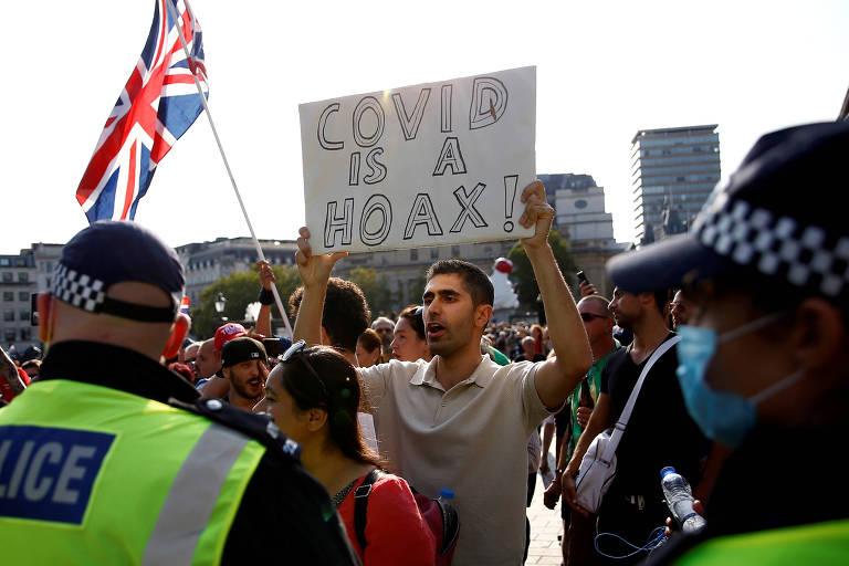 Manifestante em Londres protesta contra o 'lockdown' imposto como medida de controle do novo coronavírus com placa dizendo que a doença é uma mentira