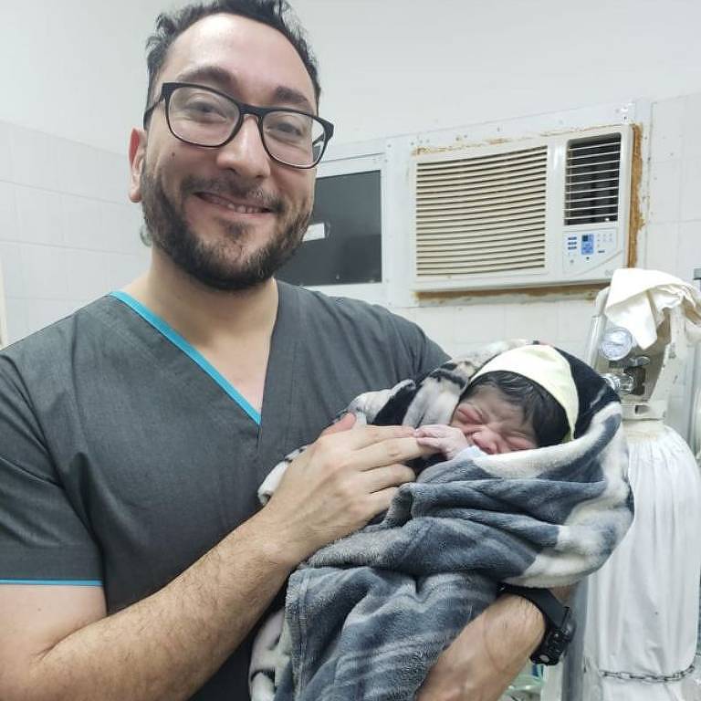 O médico Daniel Gatica segura um bebê recém nascido no colo