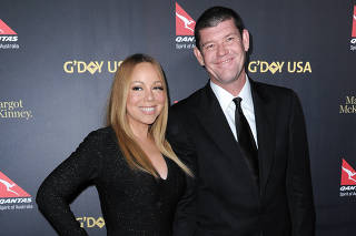 A cantora Mariah Carey de vestido longo preto ao lado do noivo, James Packer