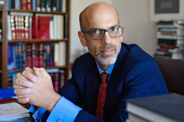 O professor Daniel Markovits, autor do livro 'A Cilada da Meritocracia', de terno e gravata em sua mesa em seu escritório na Universidade Yale