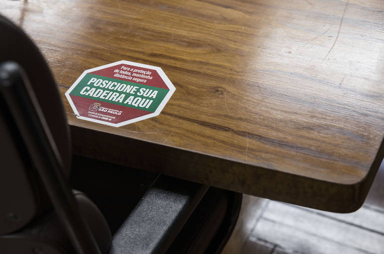 Adesivo afixado na mesa de reuniões lembra cuidados com a pandemia do coronavírus, na sala Tiradentes