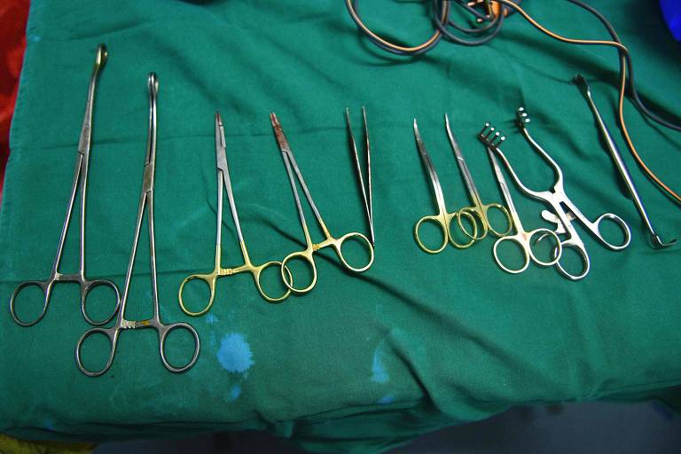 sobre pano verde, várias pinças e outros instrumentos cirúrgicos