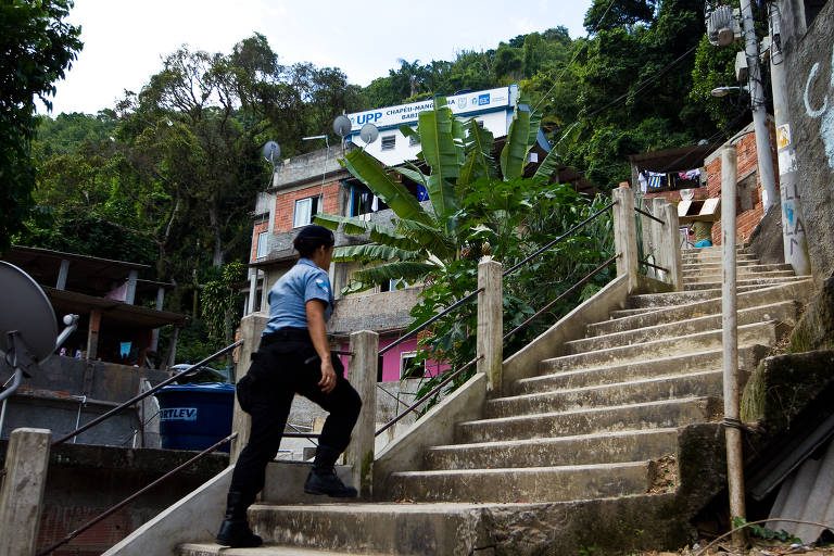 Policial sobe as escadarias que levam à UPP do Chapéu Mangueira, no Leme, em 2013. Algumas unidades funcionavam de forma eficiente, como a do Dona Marta, em Botafogo, primeira a entrar em operação; outras, como a da Mangueira, pouco mudaram a rotina da região já que continuaram os tiroteios e mortes. Algumas conseguiram diminuir a criminalidade, mas outras sofriam seguidos ataques, como as do Alemão