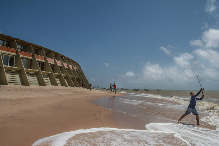 Garoto pesca na praia ao lado de estrutura do famoso hotel Tambaú, hoje fechado, em João Pessoa, na Paraíba