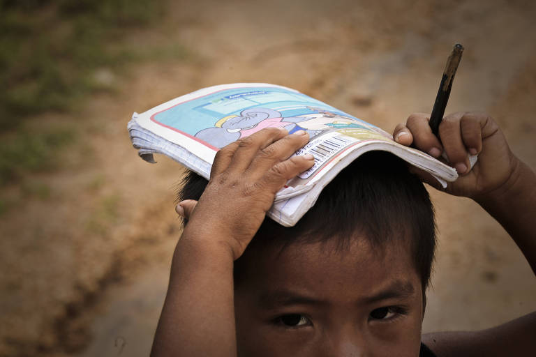 Criança com caderno na cabeça