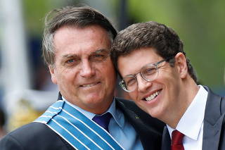 Brazil's President Jair Bolsonaro hugs Brazil's Environment Minister Ricardo Salles during a ceremony of Aviator's Day