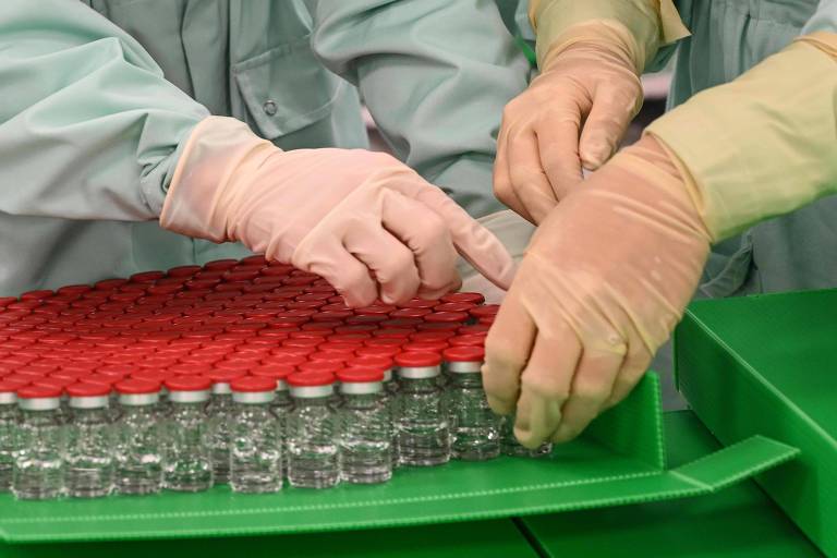 Técnicos de laboratório manuseiam recipientes para possível vacina contra a Covid-19 feita pela Universidade de Oxford
