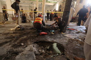 Rescue workers search for body parts at the site of a bomb blast at a religious seminary in Peshawar