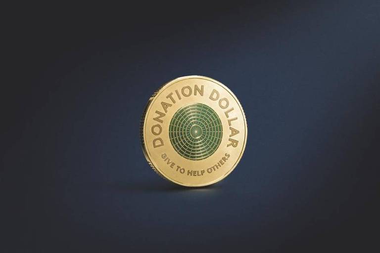 Imagem do Dólar de Doação - moeda dourada; no meio delá há um círculo com aneis também dourados sobre um fundo verde