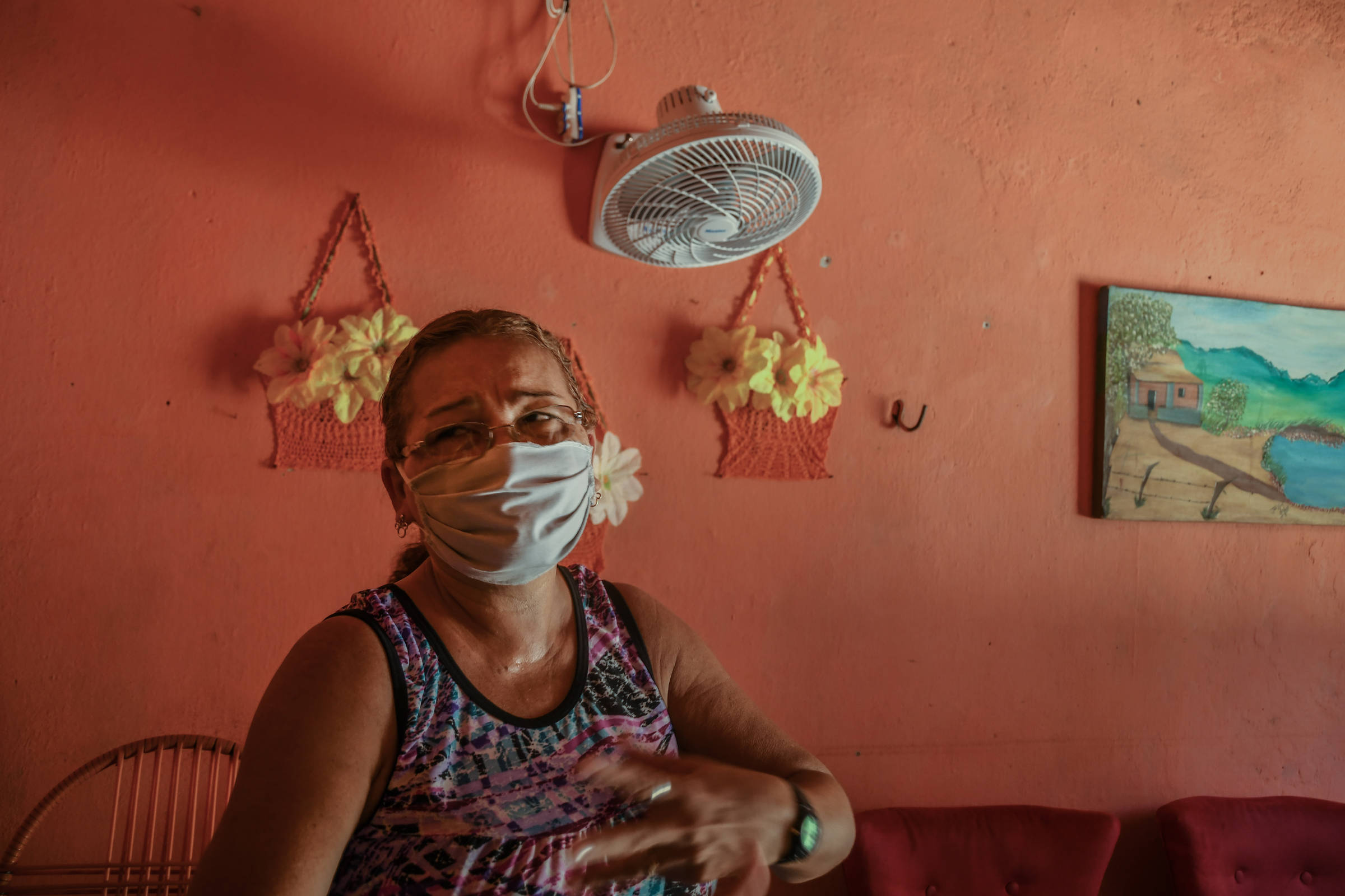 Maria da Assunção Sabino da Silva, 55, com máscara, na sala de sua casa em Terrenos Novos 2, bairro de Sobral (CE)