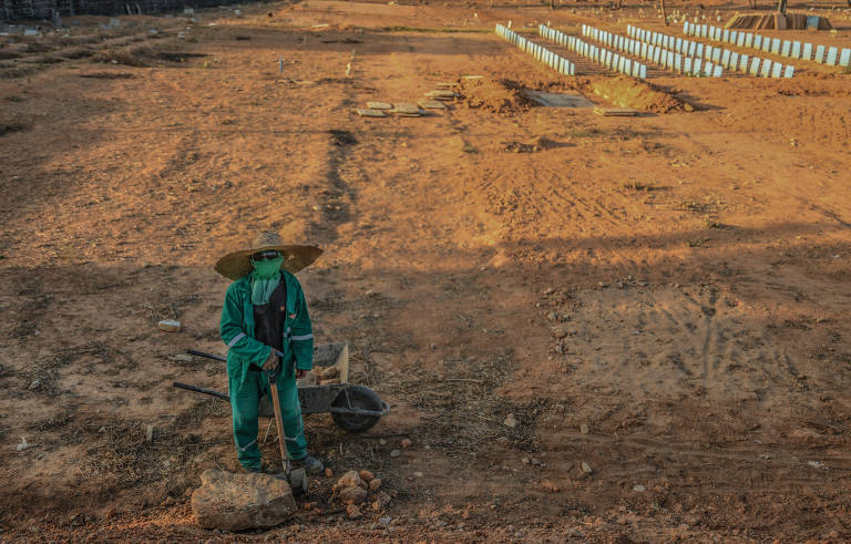 Trabalhador ao lado de carrinho de mão em área do cemitério Parque Bom Jardim, na periferia de Fortaleza (CE), onde estão enterrados ao menos 2.000 corpos de pessoas mortas durante a pandemia  –a maioria por Covid-19
 
