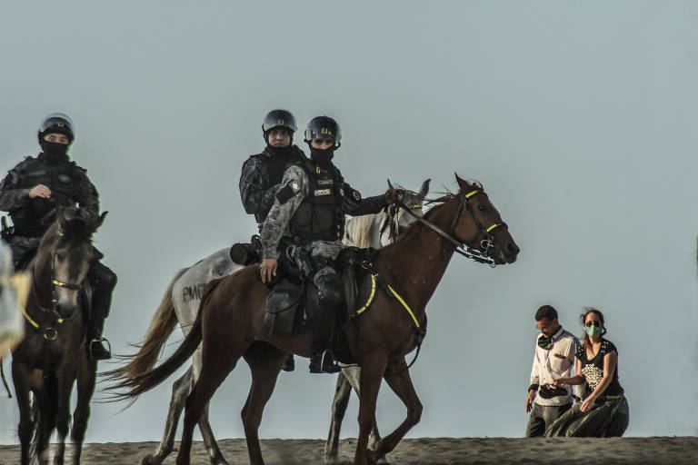 Policiais da Cavalaria com máscara circulam por praia de Fortaleza (CE) na pandemia de Covid-19 