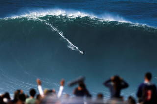 A surfer rides a large wave at Praia do Norte in Nazare