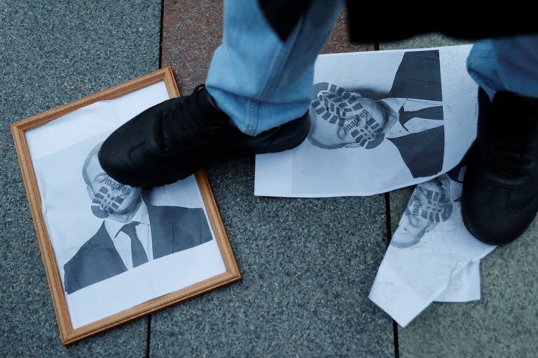 Manifestante pisa sobre retrato de Macron em protesto perto da embaixada francesa na Rússia; para os muçulmanos, pisar ou até mesmo mostrar a sola do sapato é um insulto sério