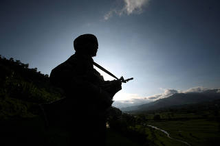 FILE PHOTO: An Indian army soldier stands guard while patrolling near the Line of Control, a ceasefire line dividing Kashmir between India and Pakistan, in Poonch