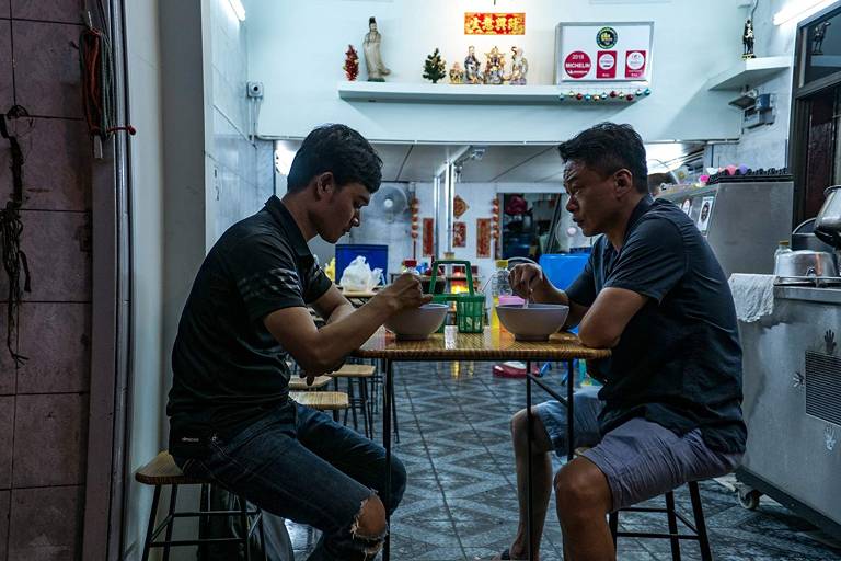 dois homens comendo numa mesa de um restaurante simples
