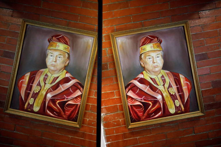 Quadro com Trump usando vestes vermelhas e douradas, com um chapéu nas mesmas cores, à moda da realeza yorubá, é visto em uma parede de madeira ao lado de um espelho que o reflete
