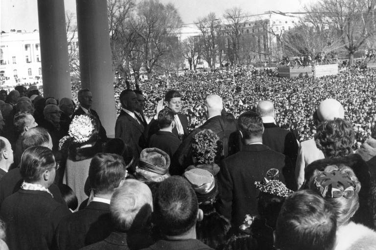 John F. Kennedy se torna o 35º presidente dos Estados Unidos em 20 de janeiro de 1961. Na foto, Earl Warren (ao centro, de costas), presidente da suprema corte, conduz o juramento de posse de JFK (centro, à esquerda), em Washington