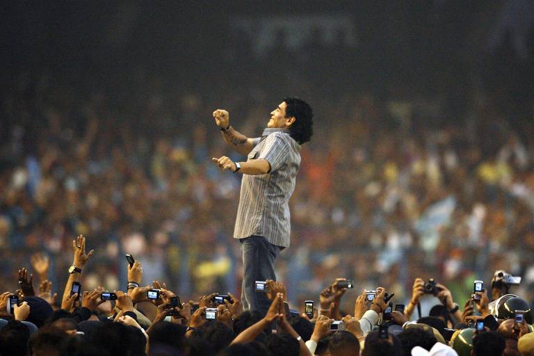 Maradona no centro, com muitas pessoas tirando foto abaixo dele