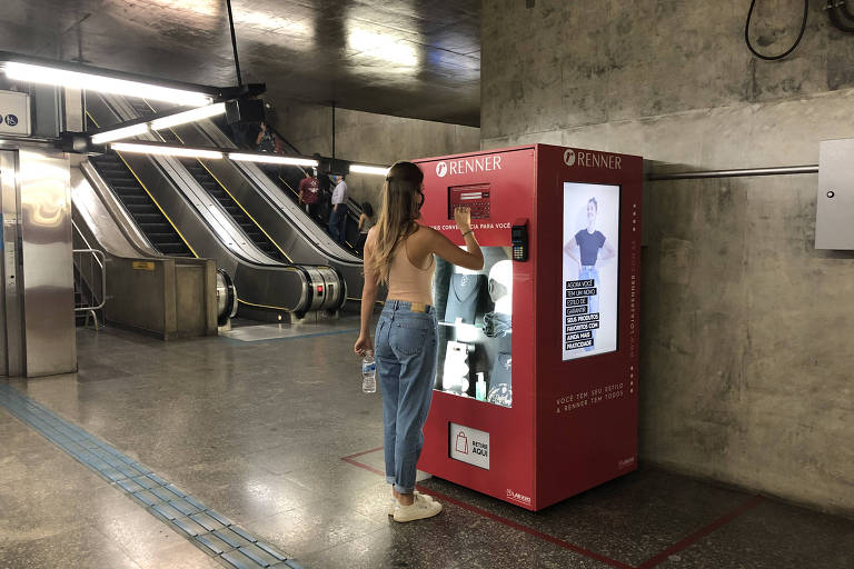 Mulher comprando na máquina de vendas automática da marca Renner no metrô São Bento