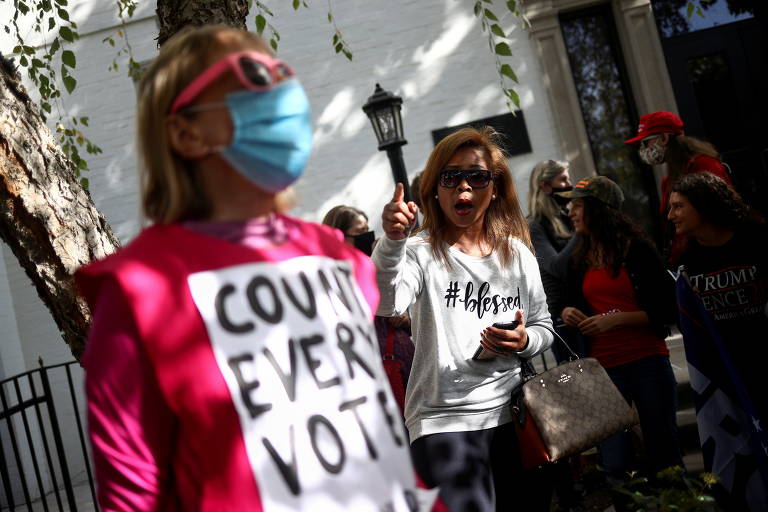 Apoiada de Trump aponta para manifestante pró-Biden, com cartaz 'contem todos os votos', próximo ao Comitê Nacional do Partido Republicano, em Washington