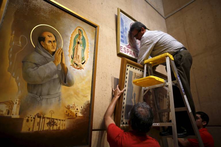 Homem tiram pintura de parede ao lado de imagem de santo com halo