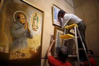 Ramiro Montes hangs paintings in a new chapel in honor of Friar Junipero Serra, who will be canonized next week by Pope Francis, at the Cathedral of Our Lady of the Angels in Los Angeles