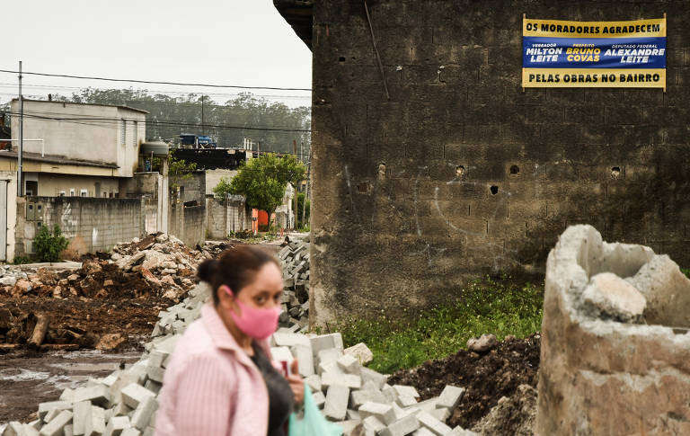 Mulher passa em frente a obra com placa que agradece a Milton Leite