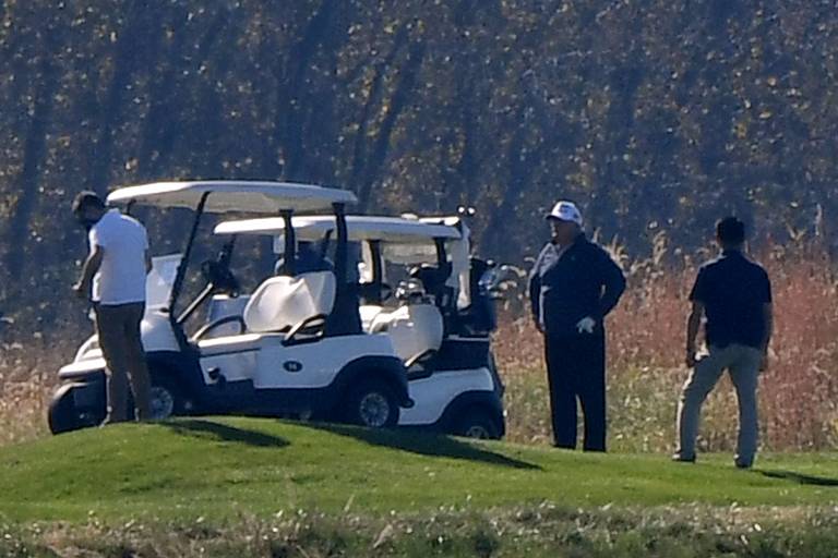O presidente Donald Trump, de boné, em seu campo de golfe particular
