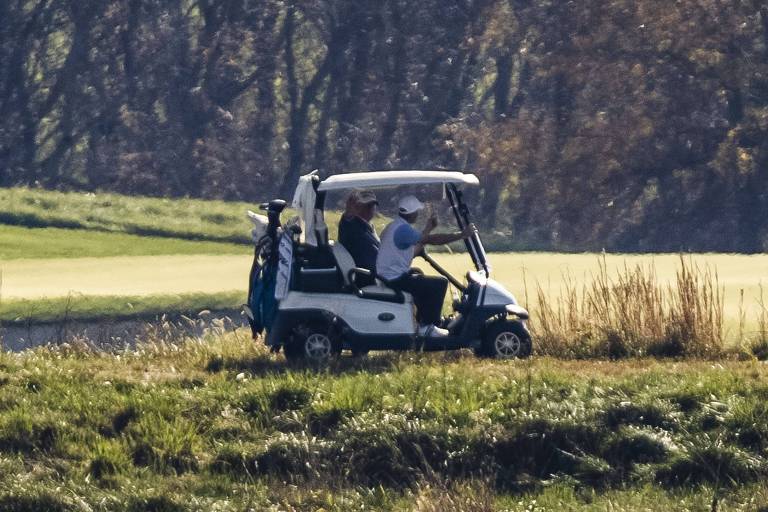 Em um carrinho de golfe, o presidente Donald Trump acena para a imprensa em Sterling, na Virginia