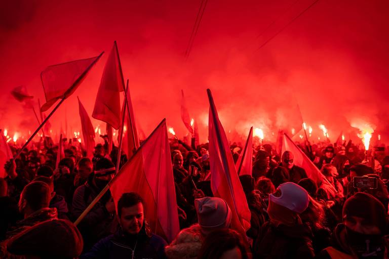 Simpatizantes da ultradireita carregam bandeiras em meio à fumaça de sinalizadores vermelhos durante marcha no Dia da Independência da Polônia, em Varsóvia
