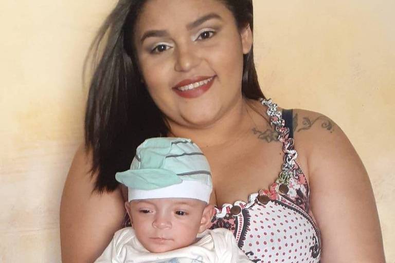 Mulher carrega bebê vestido sentado no colo